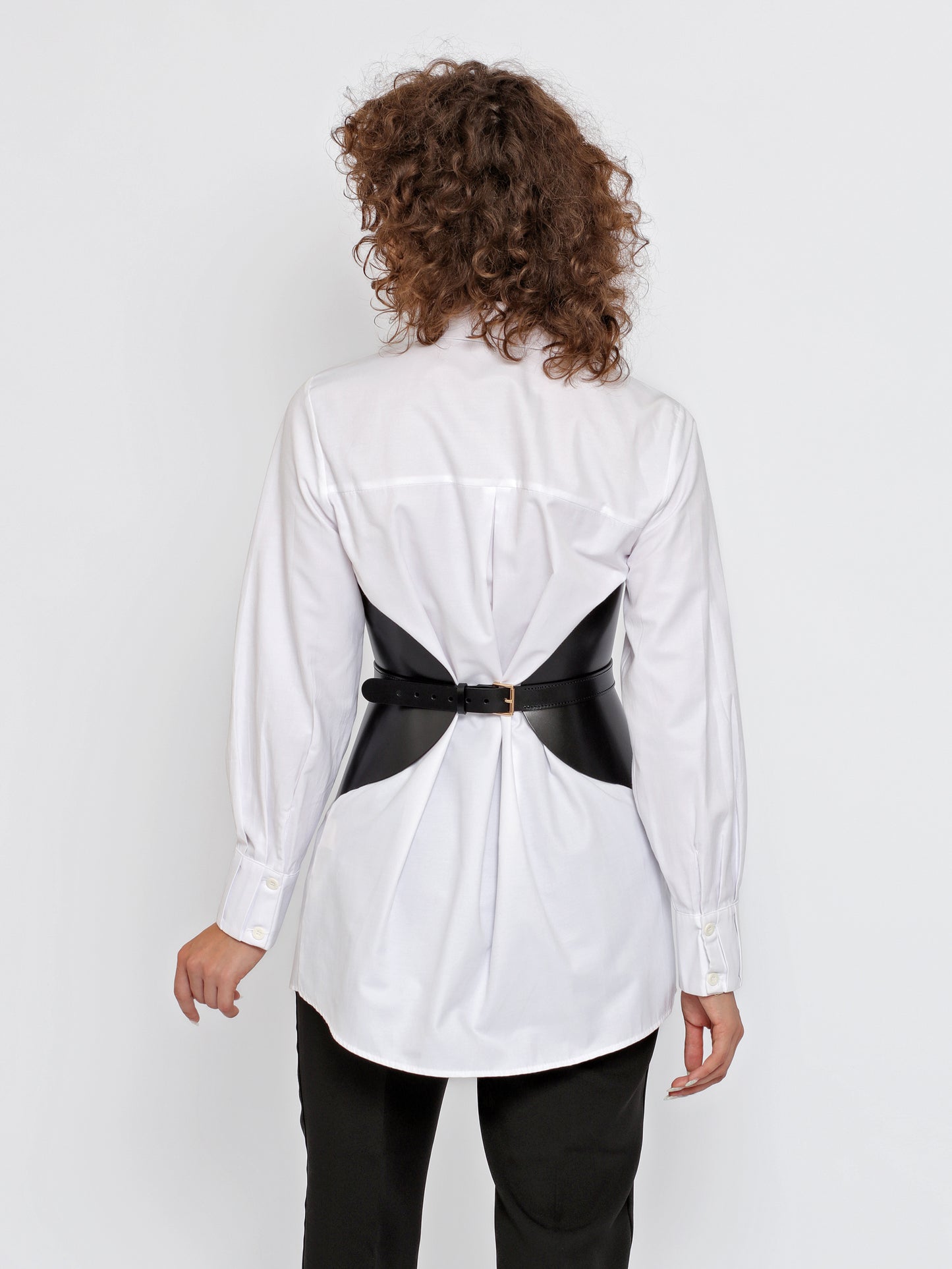 Back view of women corset belt worn by model over white shirt.