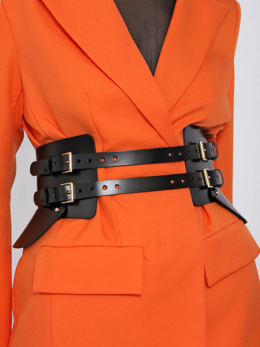 Close view of black corset belt being worn over orange blazer.