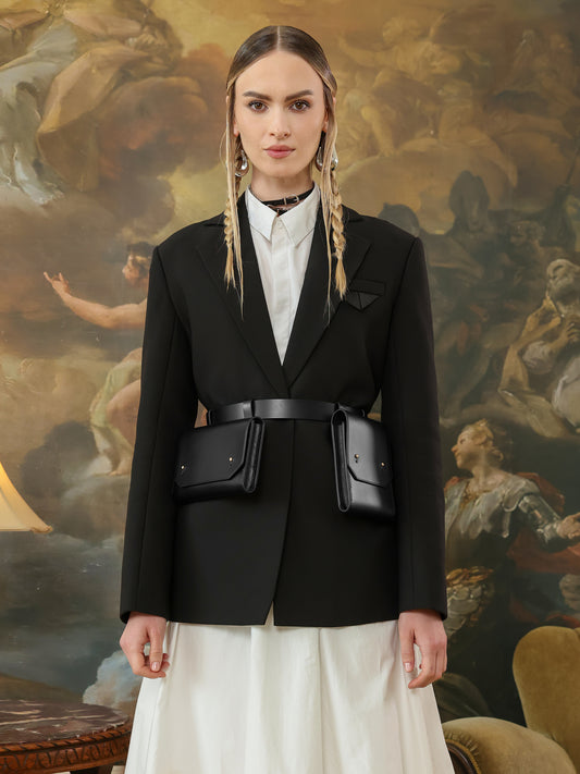 Black leather envelope belt bag with two pockets on women’s blazer.