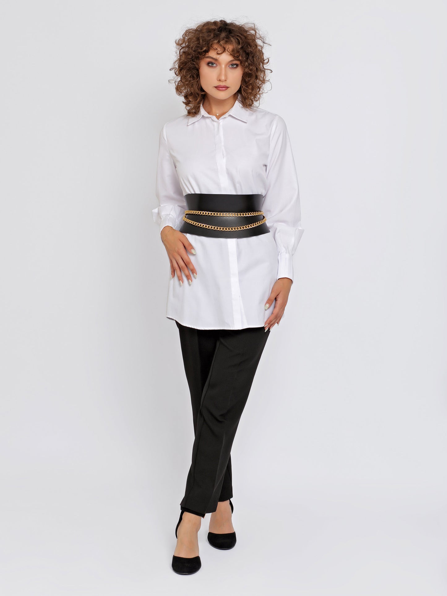 Full outfit view of black leather corset belt being worn over white shirt and black trousers.