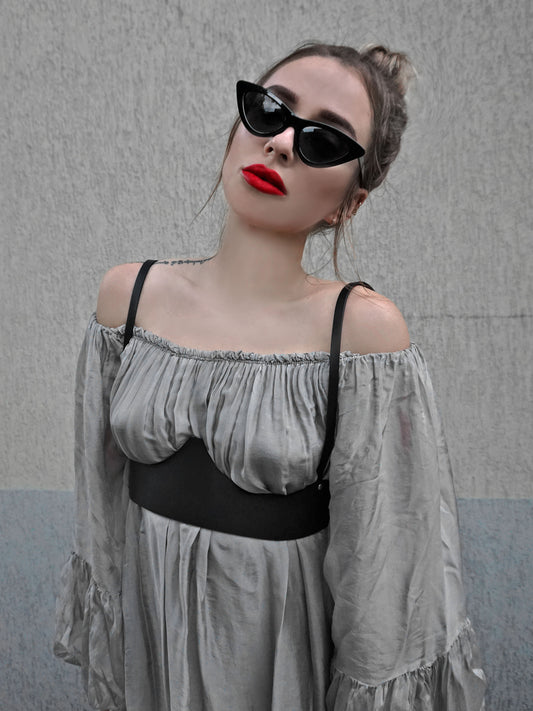 Black leather underbust harness worn over gray dress
