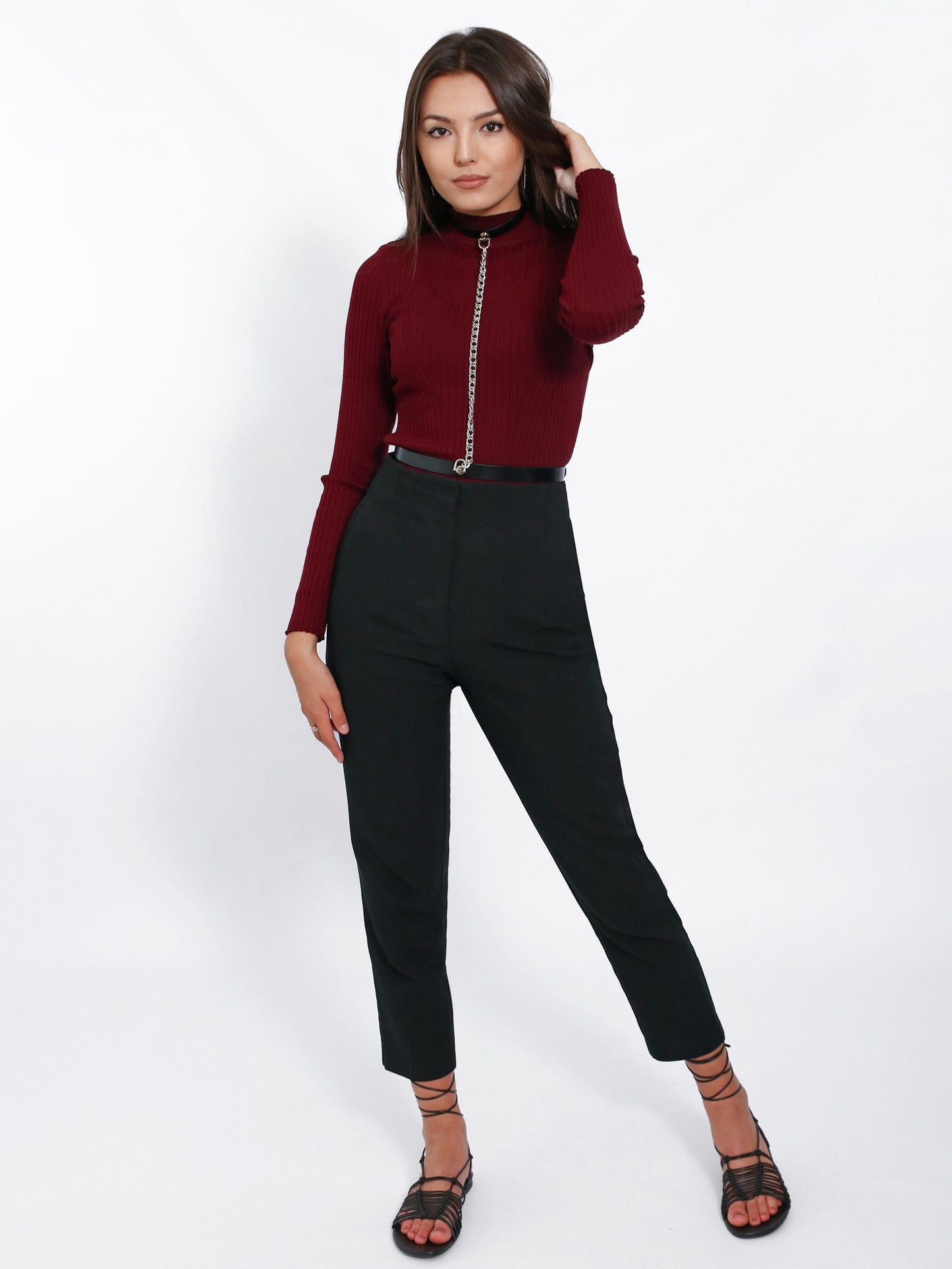 Black slim leather chain harness worn over burgundy turtleneck.