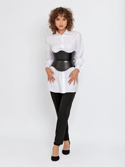 Full outfit view black corset belt worn over white shirt by model.