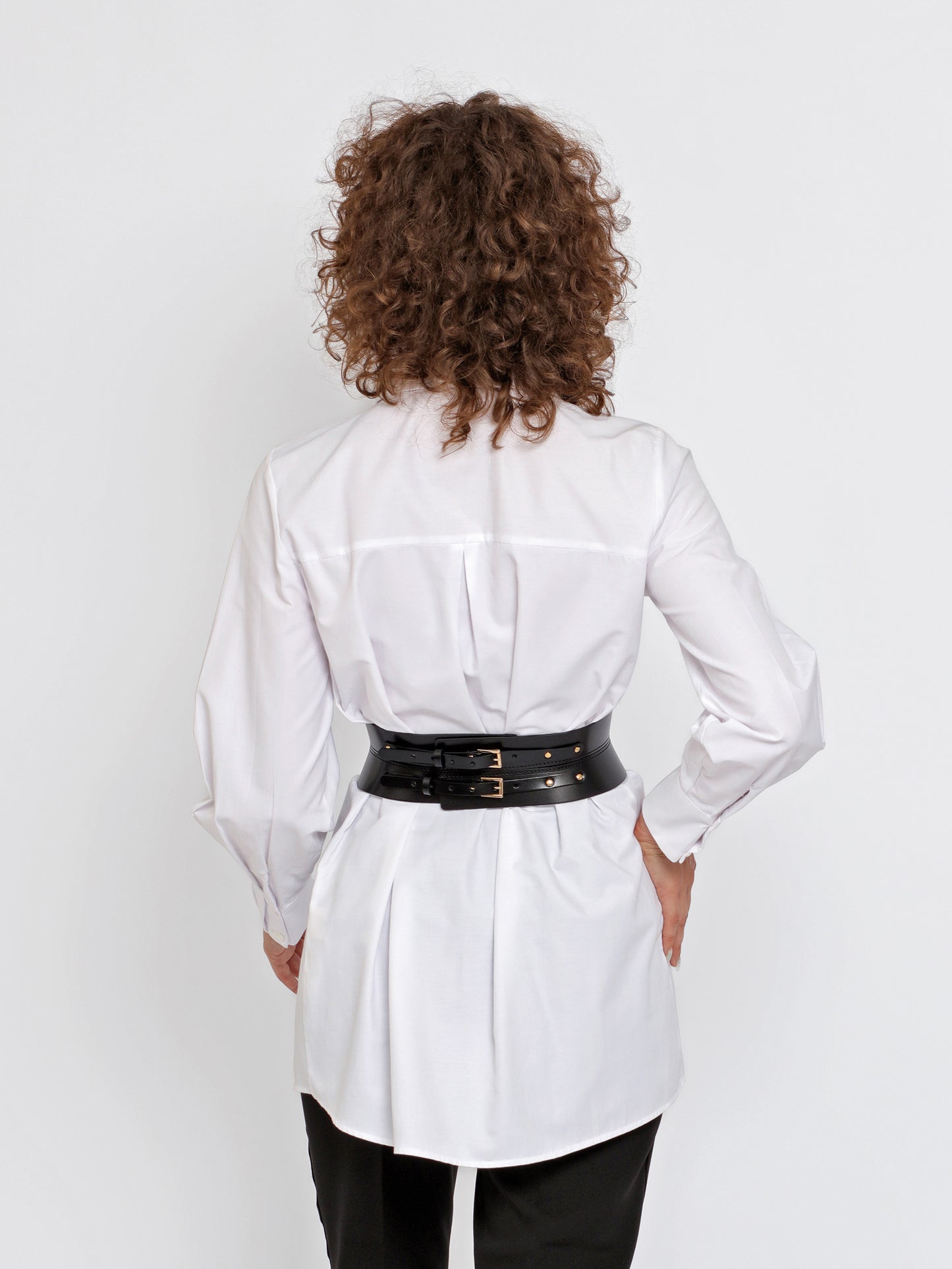 Back view of black corset belt being worn over white shirt.