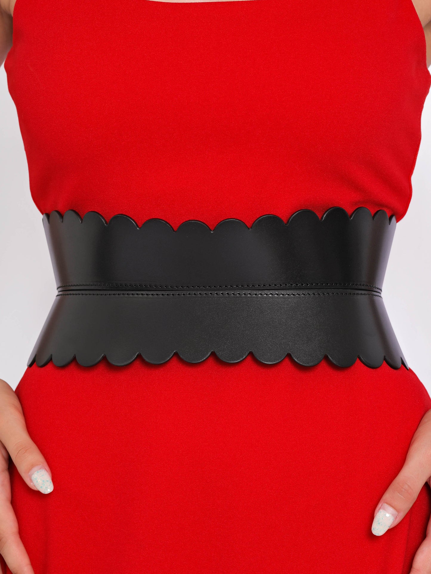 Close view of black hourglass belt being worn over red dress.