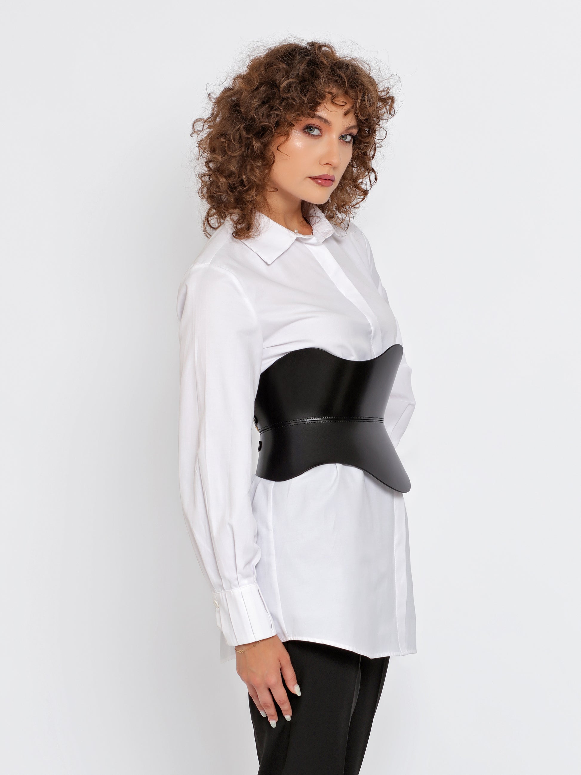 Side view of black leather corset worn over white shirt by model.