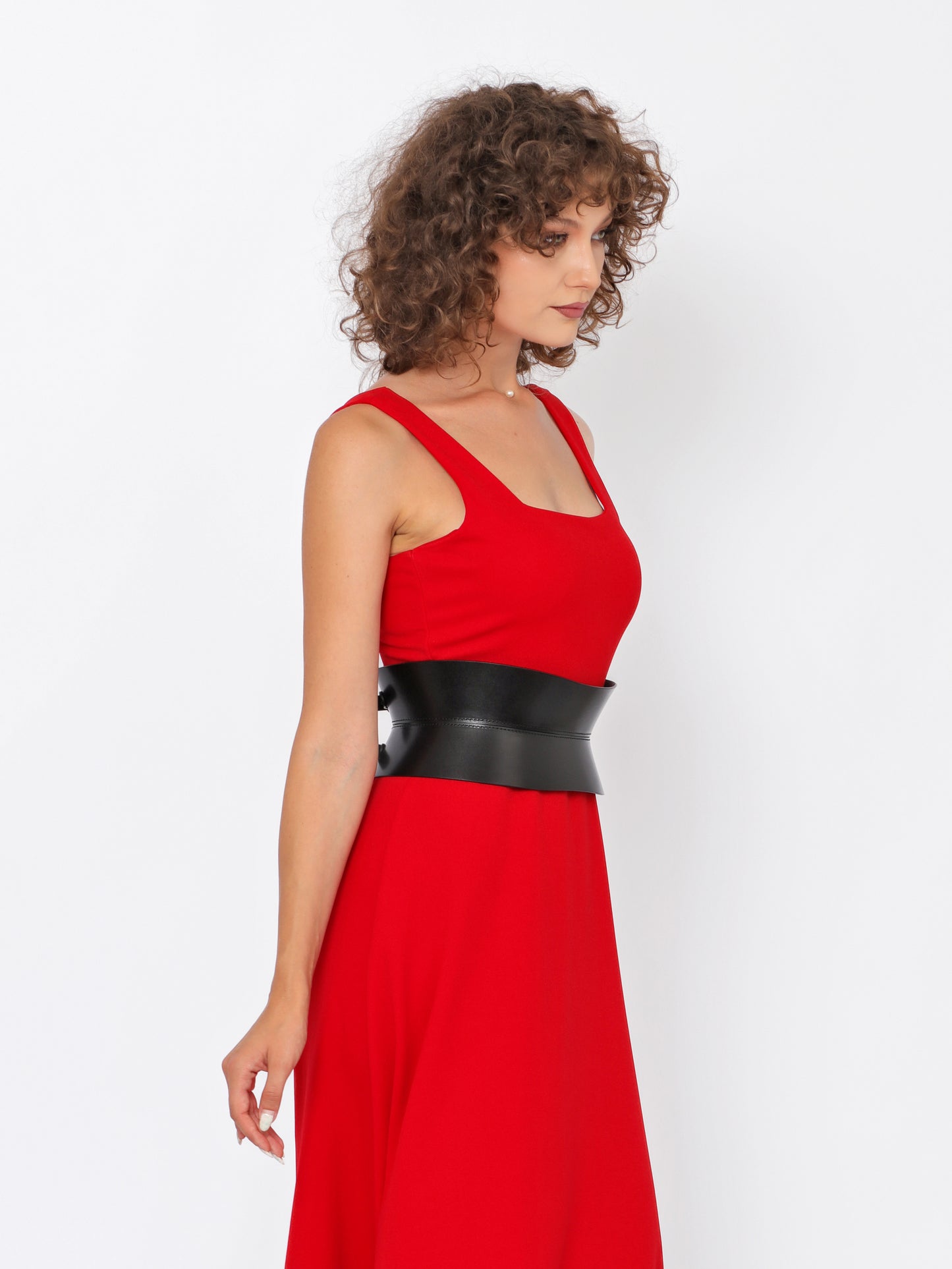 Side view of black corset belt being worn over red dress.