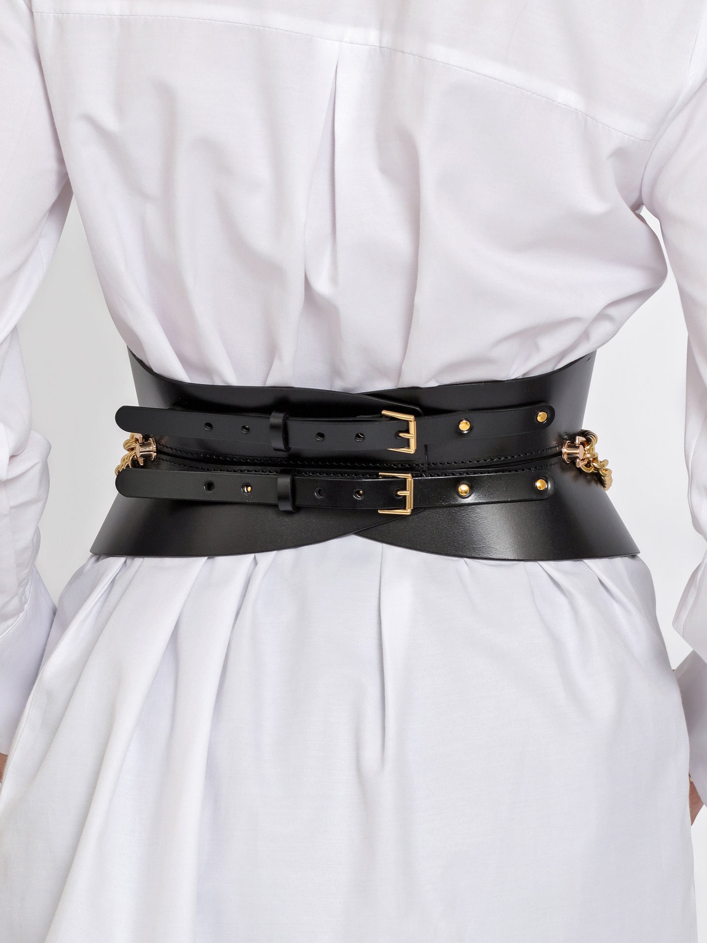 Back view of black leather corset belt being worn over white shirt.