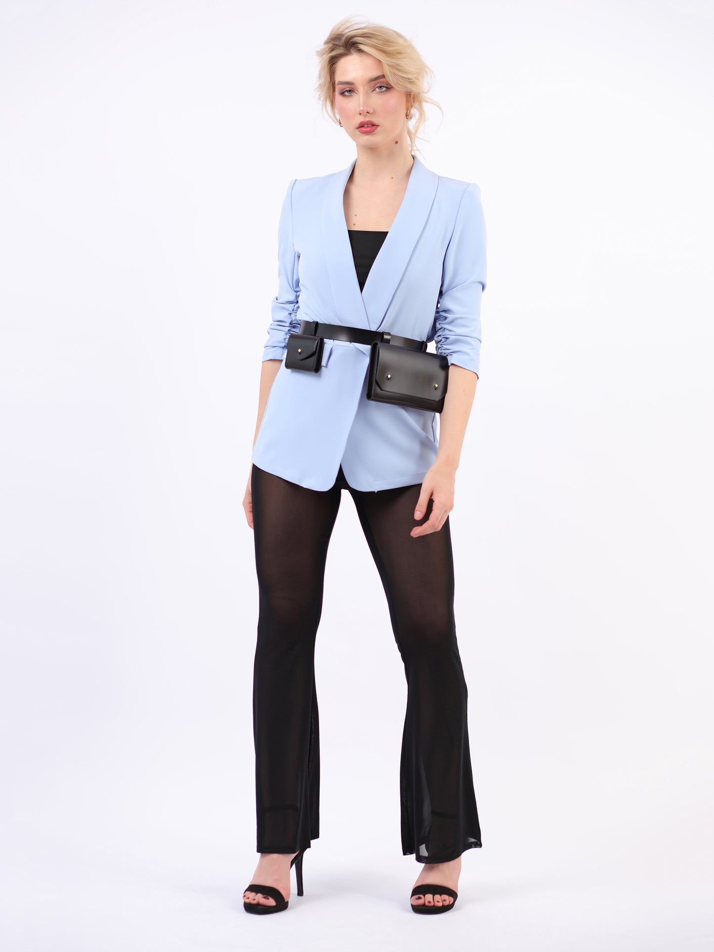 Black double belt bag fitted on woman wearing blue blazer and black trousers.