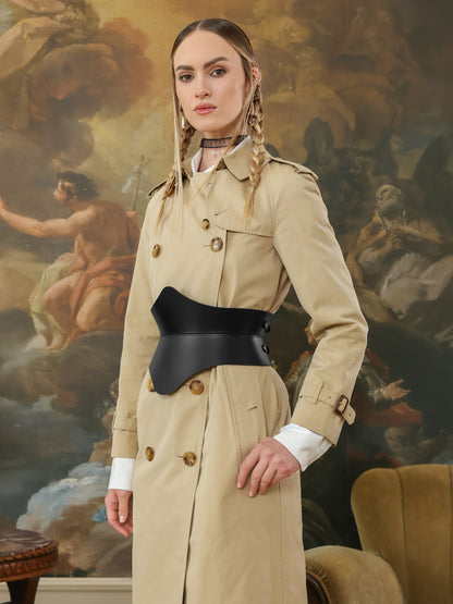 Woman wearing black hourglass corset belt over beige trench coat.
