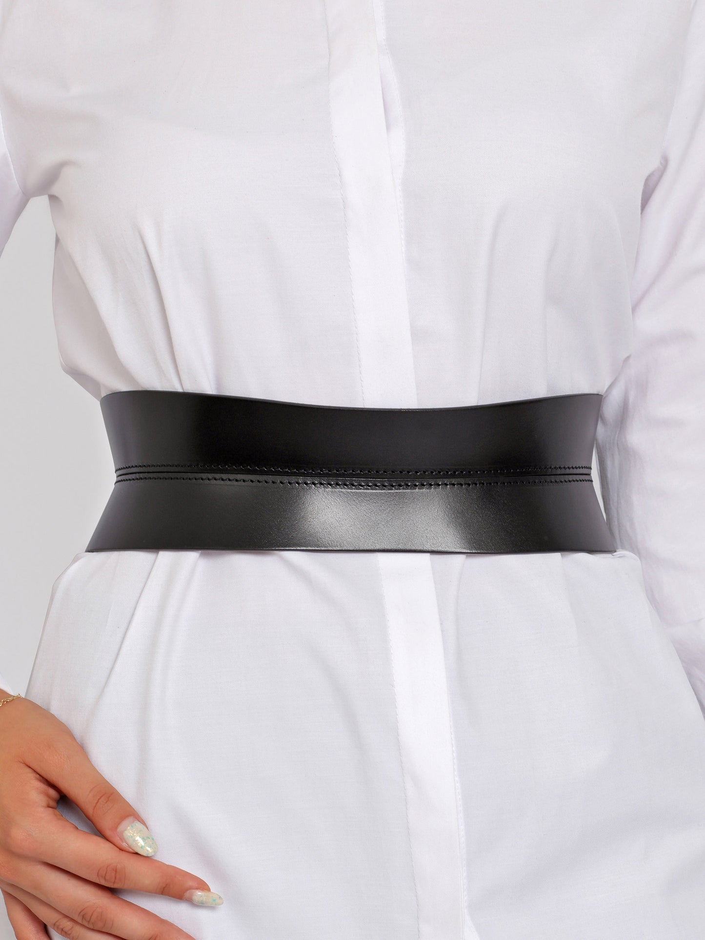 Close view of leather corset belt being worn over white shirt.