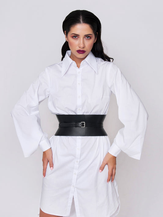 Black leather corset belt fitted on woman wearing white shirt dress.