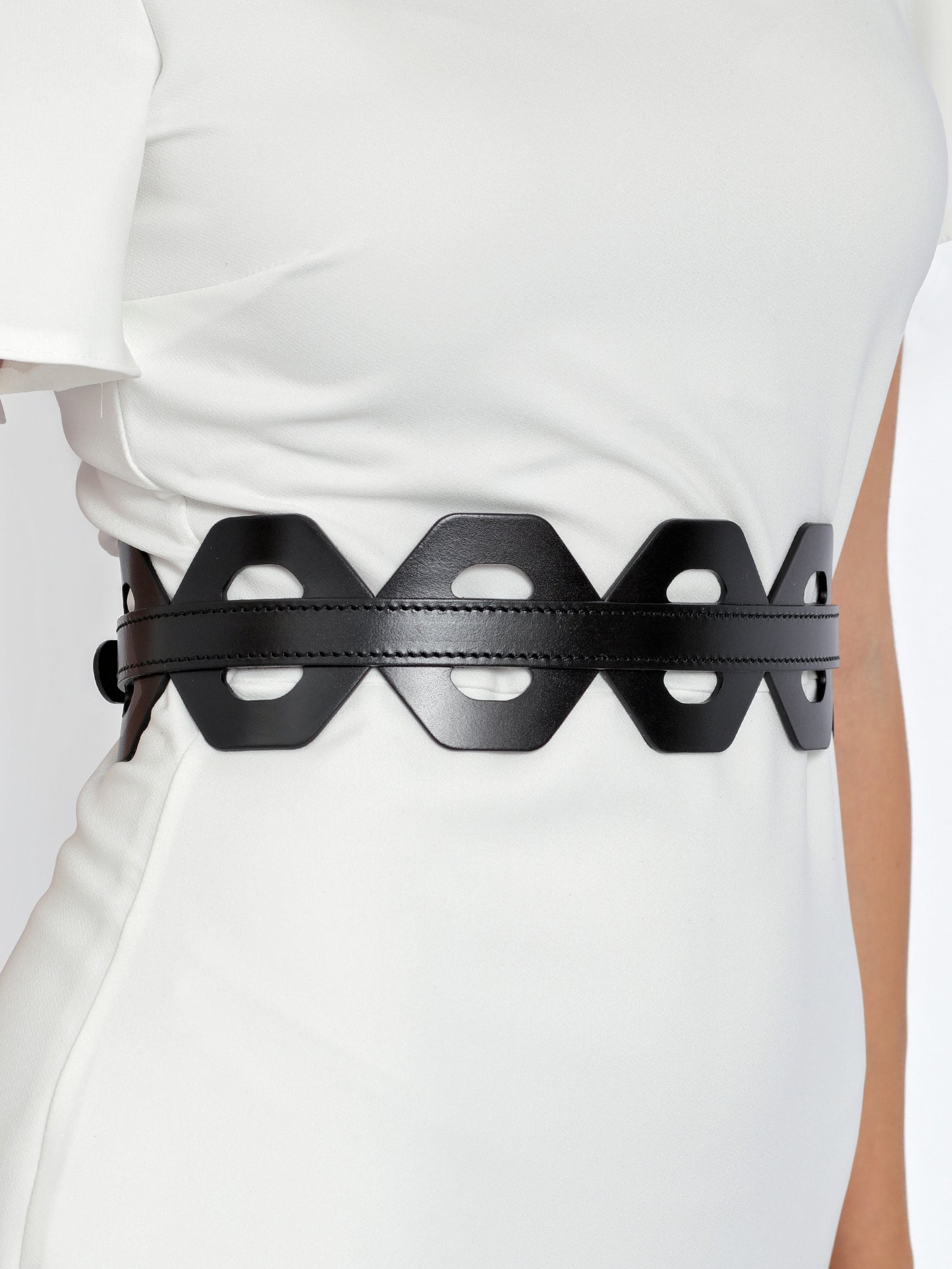 Close view of cutout wide leather belt being worn over white dress.