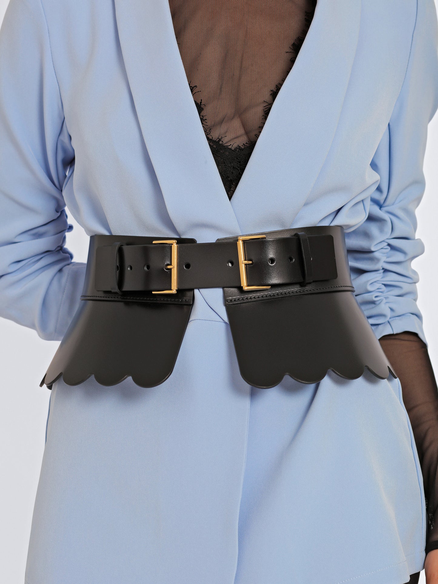 Close view of black leather corset belt being worn over blue blazer.