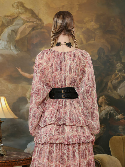 Woman in a paisley dress styled with a wide black leather underbust belt, creating a defined silhouette.