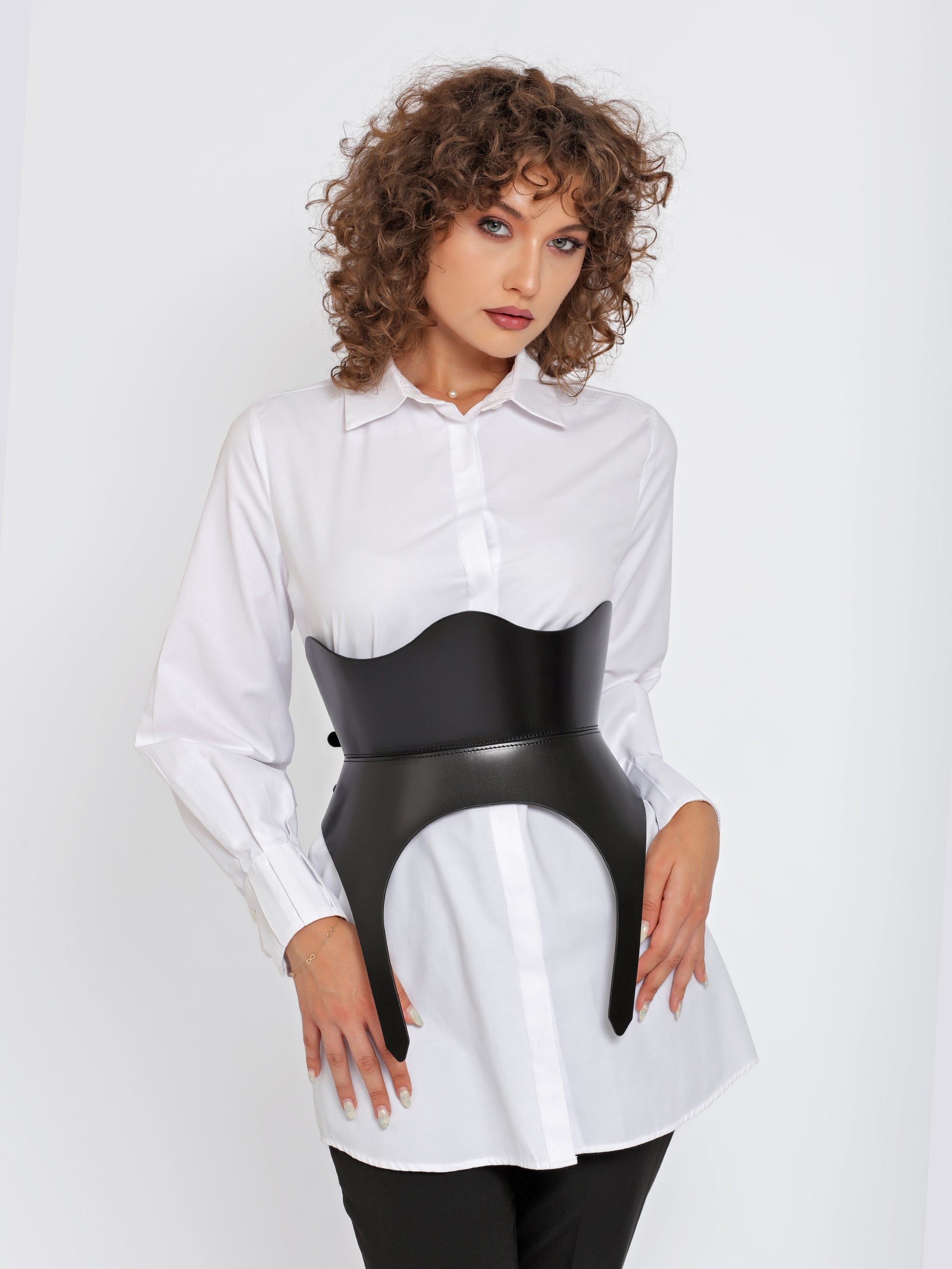 Front view of black corset belt worn by model over white shirt.