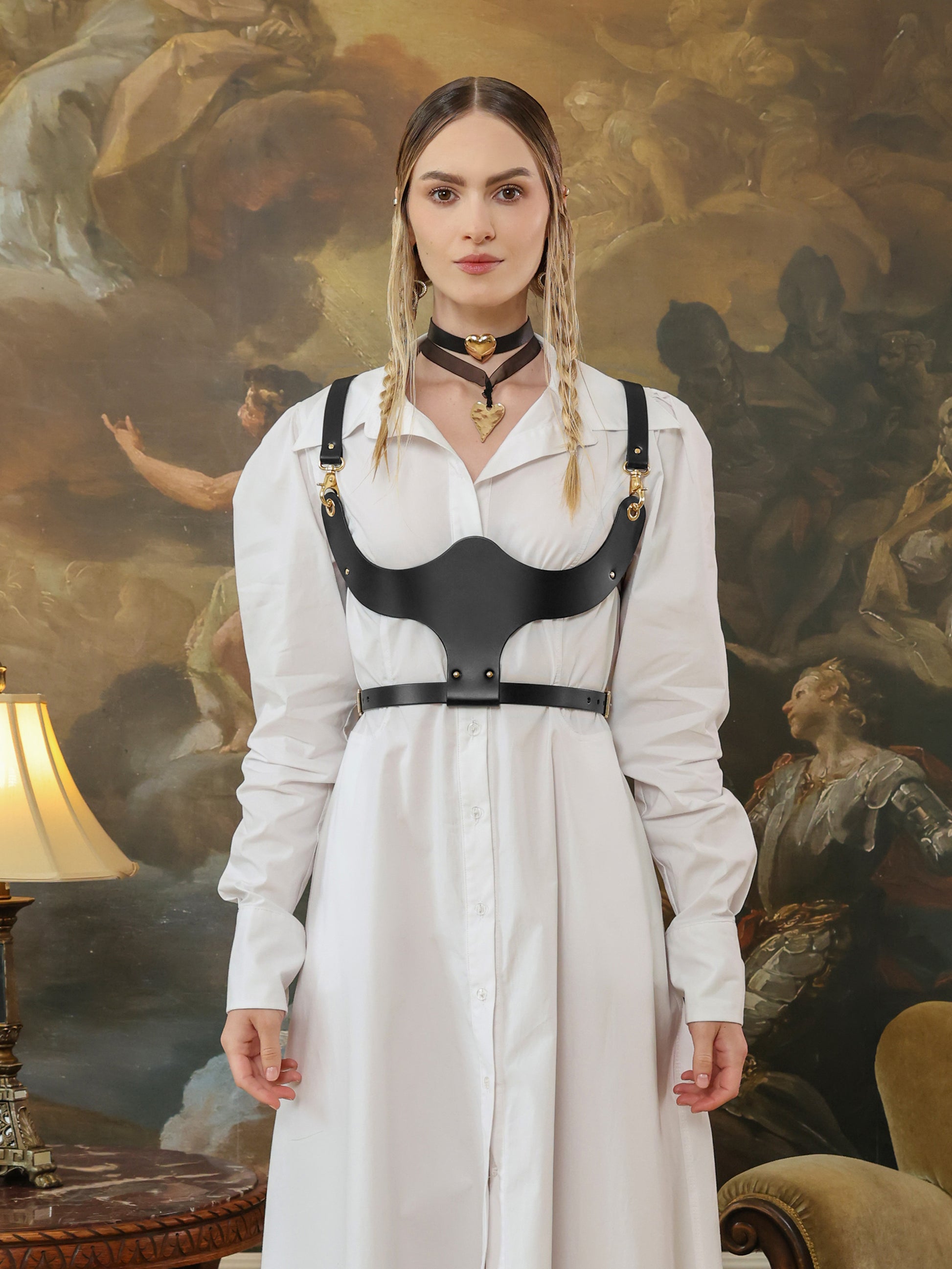 Fashion look featuring a black leather underbust harness worn over a white shirt dress, front view.