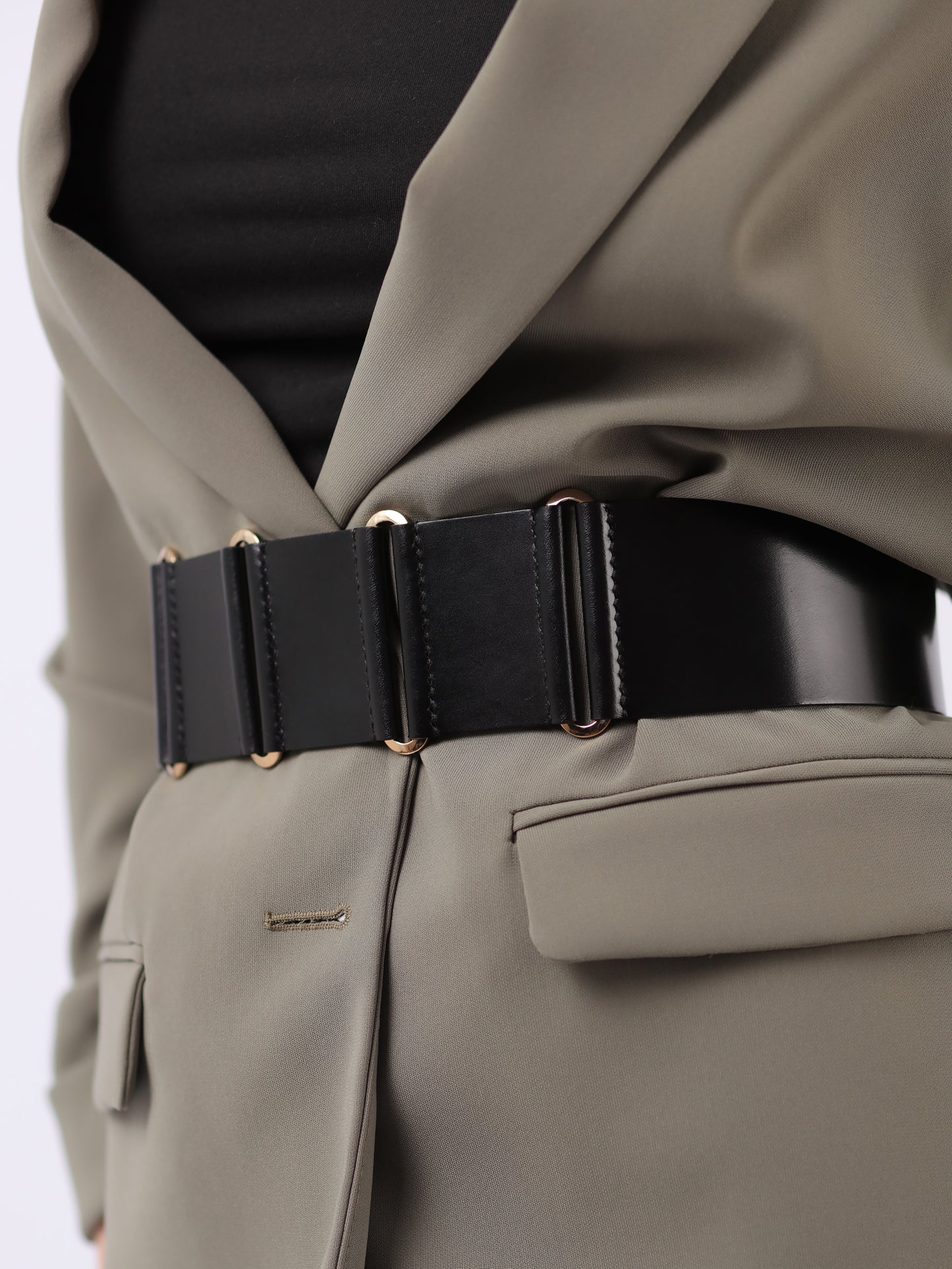 Detailed view of black wide leather belt.