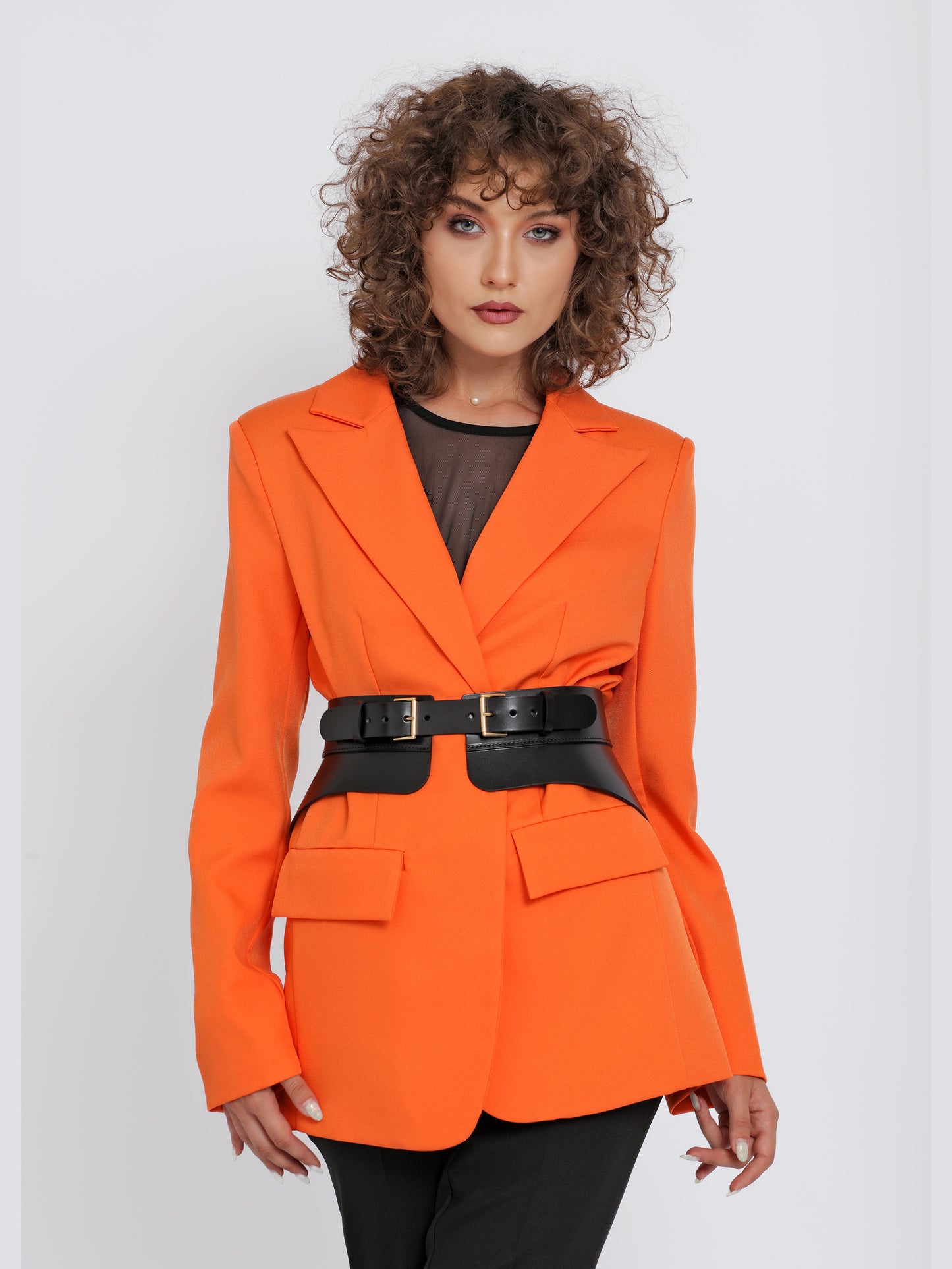 Front view of black leather peplum belt being worn over orange blazer.