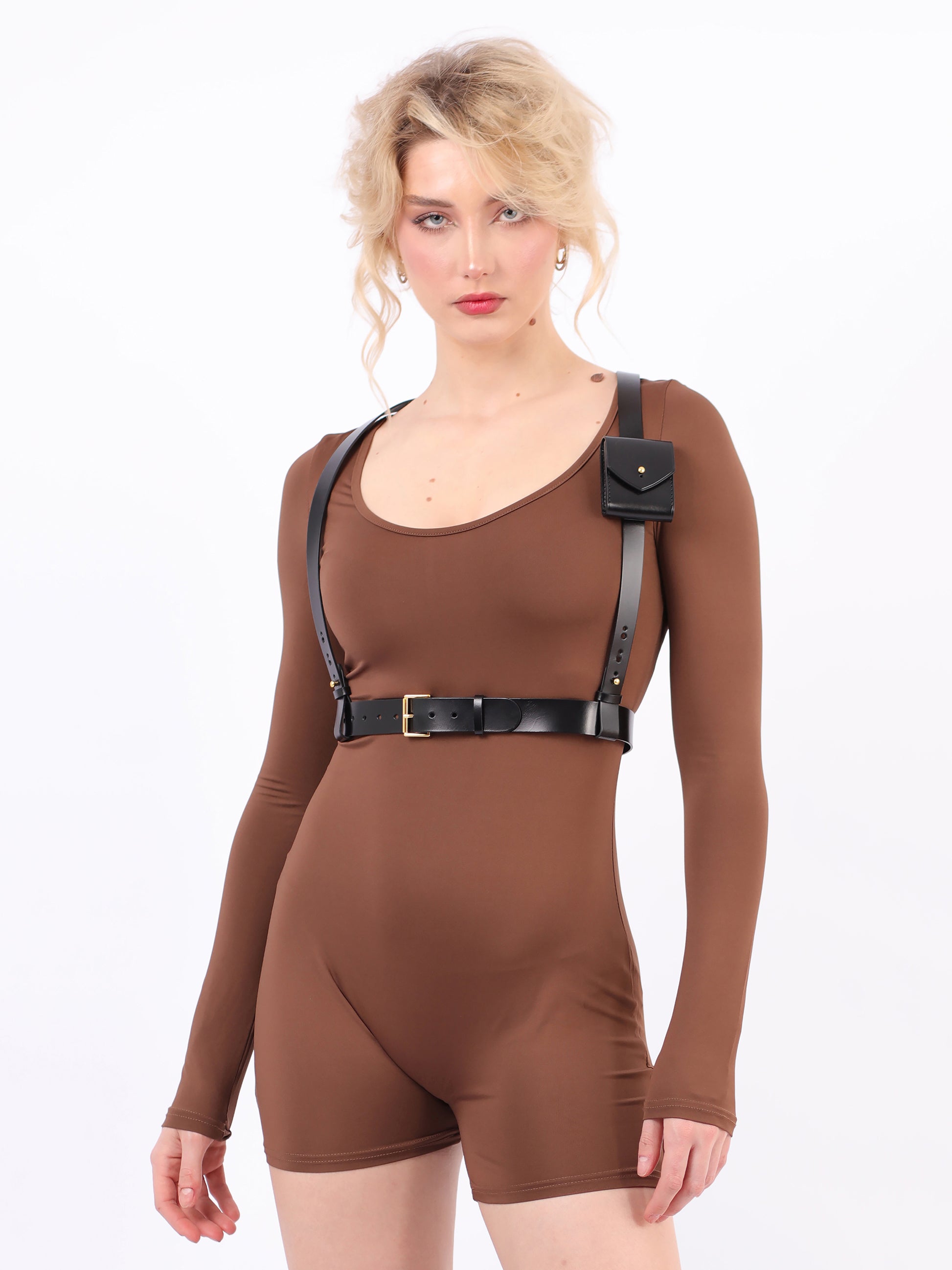 Black leather pocket harness worn over brown jumpsuit.