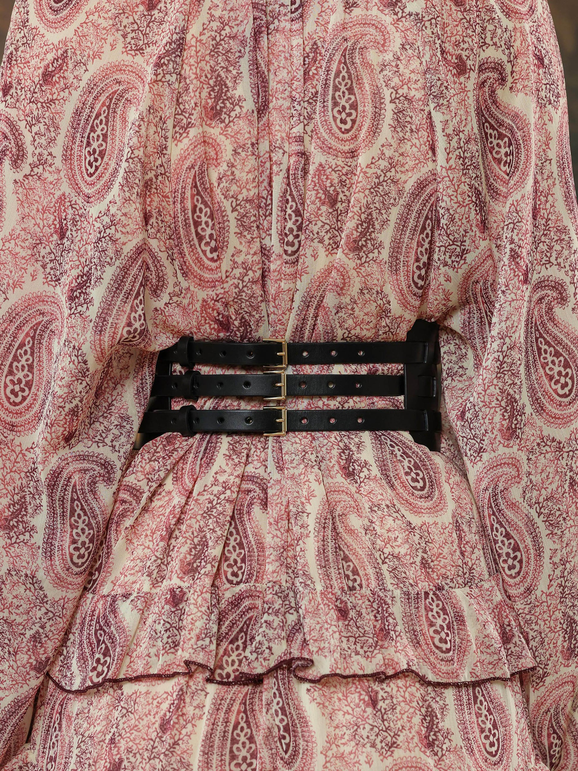 Black wide corset-style belt with geometric cutout design, styled over a patterned dress.