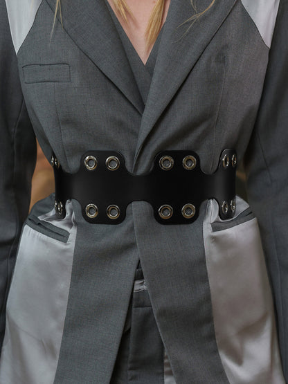 Close-up of black leather waist belt with silver eyelets on grey blazer.