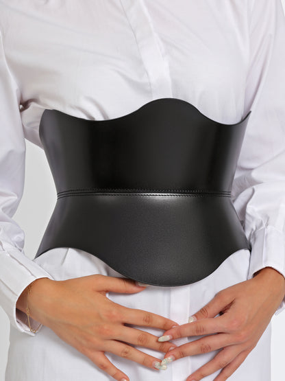 Close up view of black leather wide belt worn over white shirt by model.