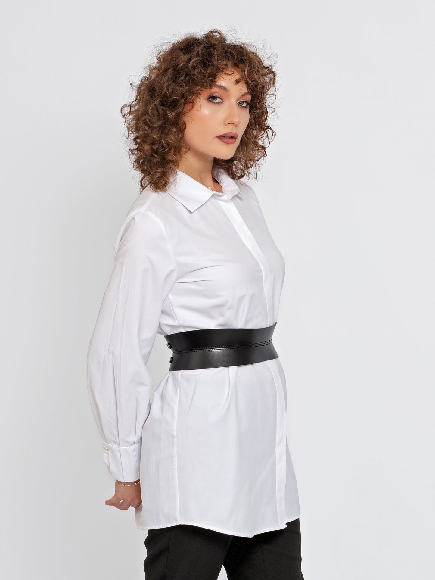 Side view of hourglass shaped belt being worn over white shirt.