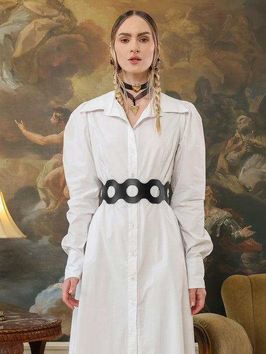 Black leather corset-style belt with large cutout circles, styled over a white shirt dress.