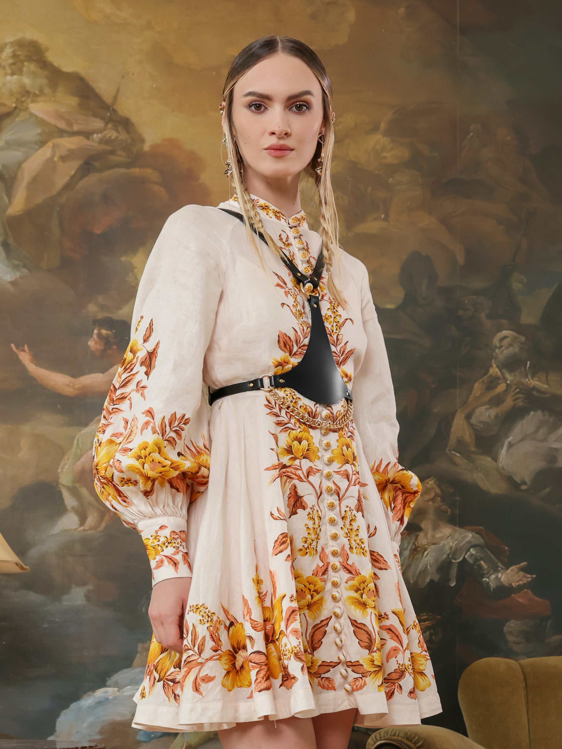 Woman in floral embroidered dress styled with leather chain harness.