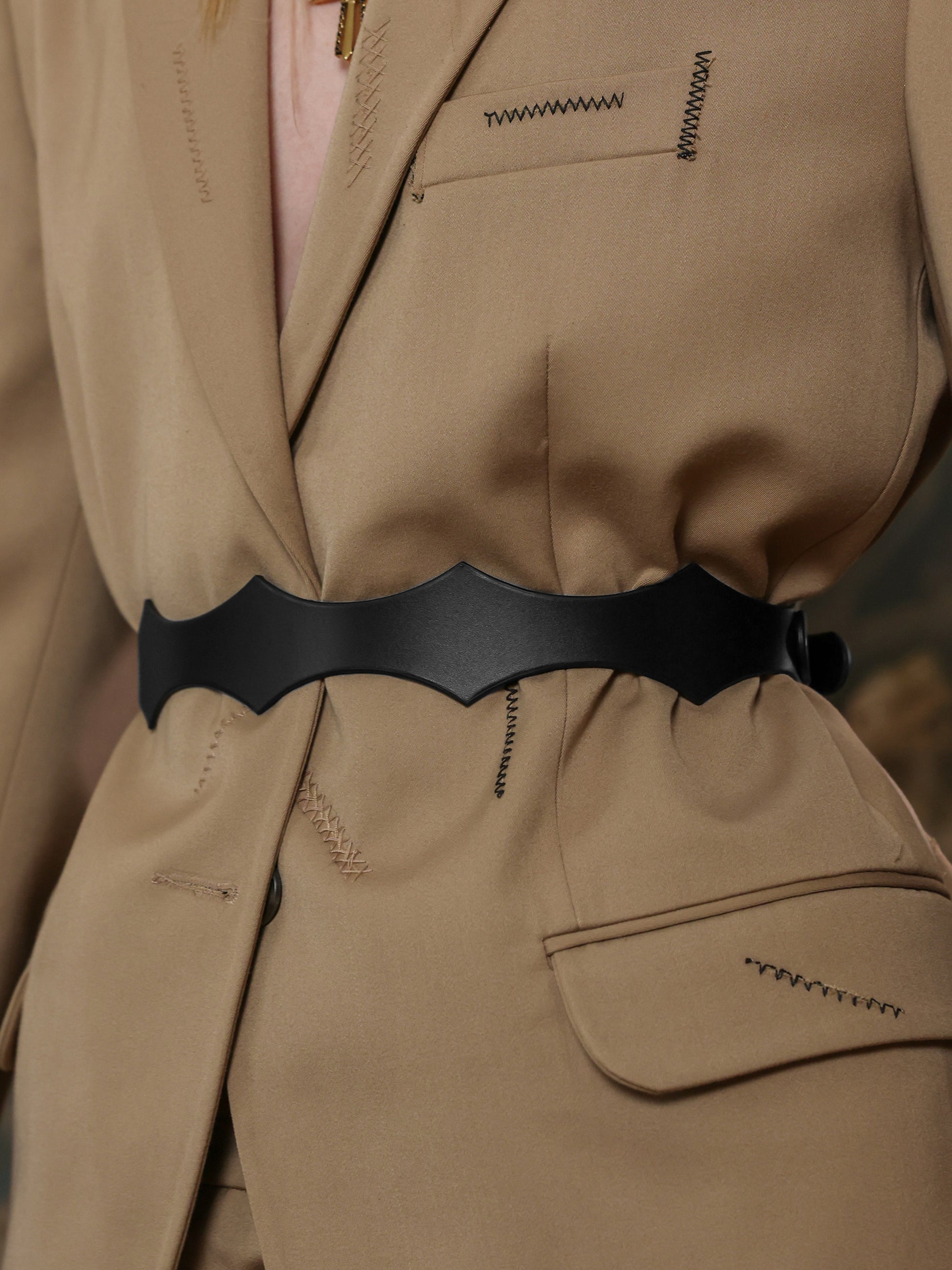 Back view of a beige suit styled with a black leather waist belt.
