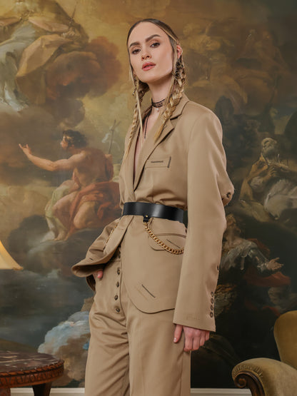 High-waist black leather belt with gold chain embellishments, paired with a beige pantsuit.