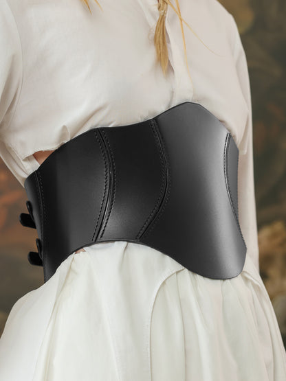 Side view of a wide black leather corset belt with curved seams, styled over a white outfit for a modern statement.