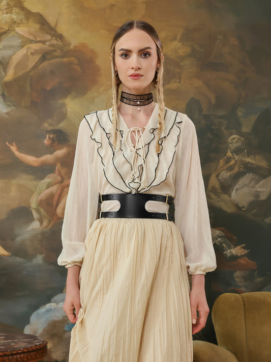 Woman in a white blouse and beige skirt wearing a black leather wide belt.