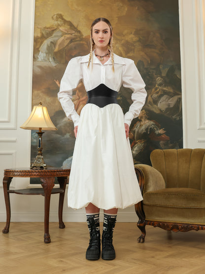 A woman in a white dress shirt and skirt wearing a black leather hourglass corset belt, paired with black lace-up boots and statement socks.