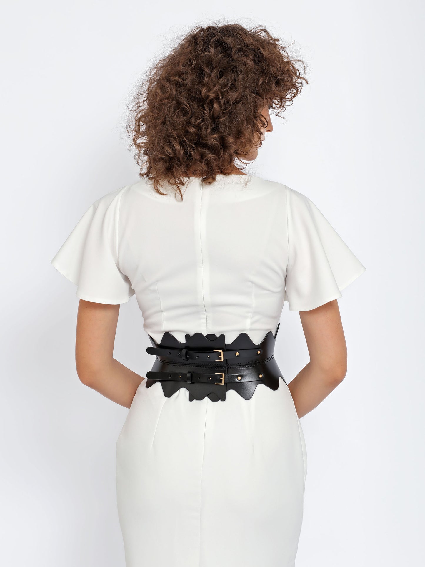 Back view of scalloped hourglass belt being worn over white dress.