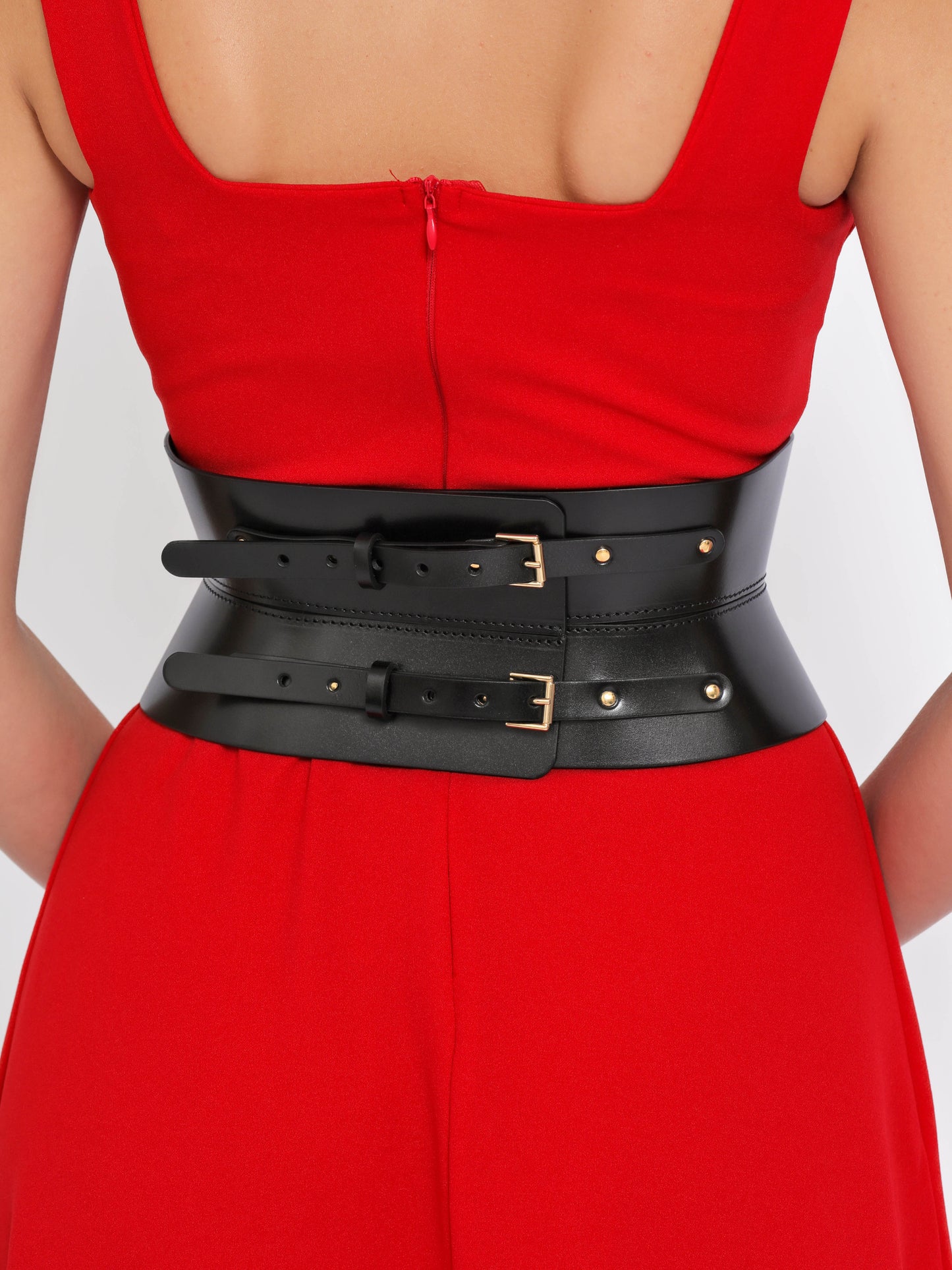 Back view of black leather belt being worn over red dress.