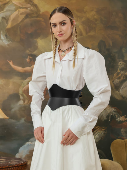 Side view of a woman in a white shirt dress styled with a black leather hourglass corset belt, accessorized with gold jewelry.