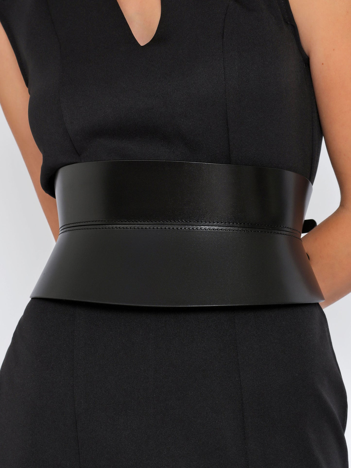 Close view of black corset belt being worn over black dress.