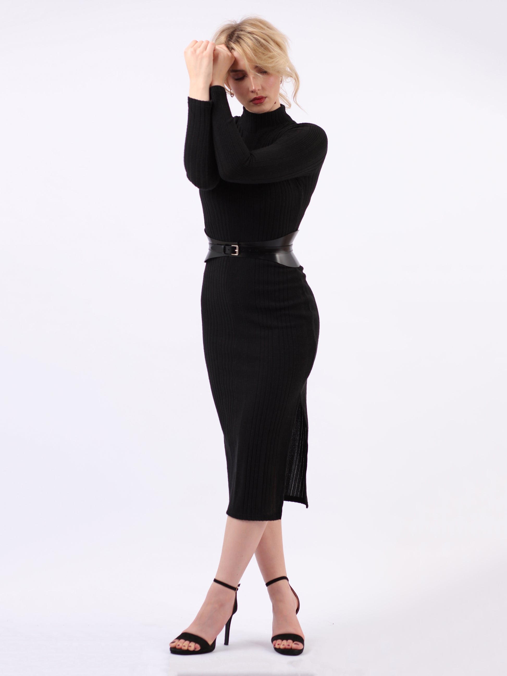 Black leather corset belt fitted on woman wearing black dress.