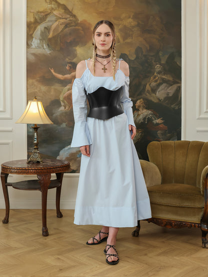 Woman wearing a black leather underbust corset with a light blue maxi dress and studded sandals.