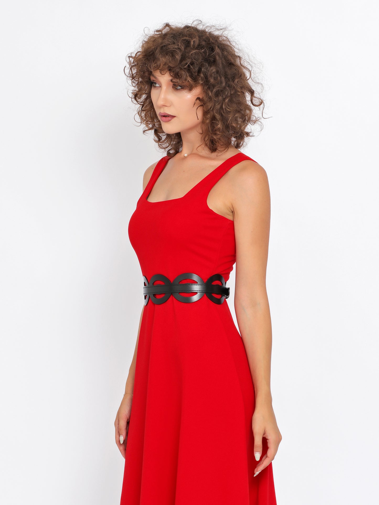 Side view of black leather high waist belt being worn over red dress.