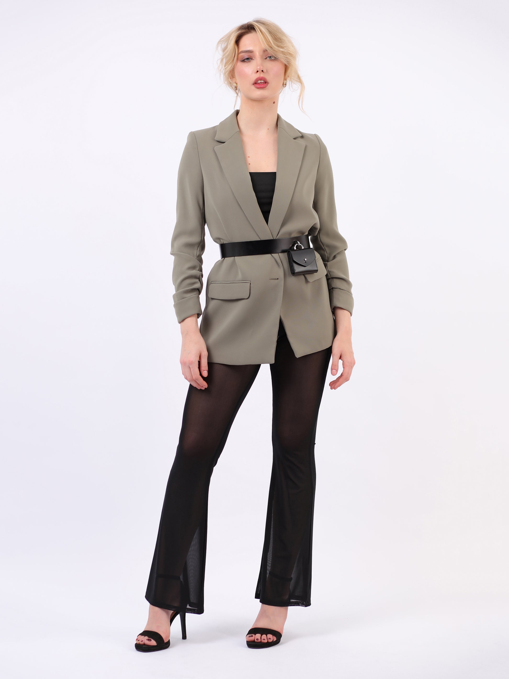 Leather micro waist belt bag fitted on woman wearing green blazer and black trousers.