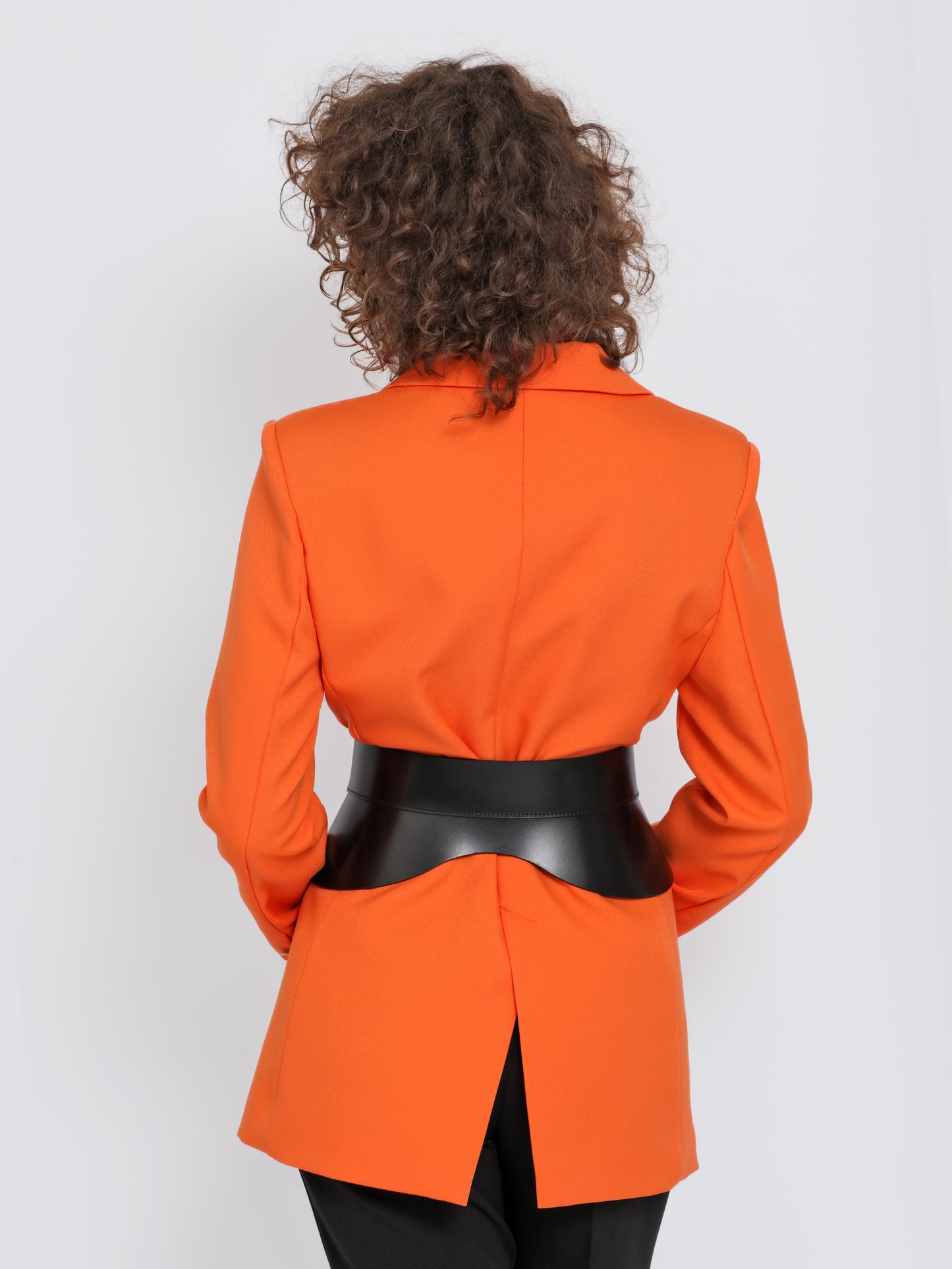 Back view of black peplum belt being worn over orange blazer.