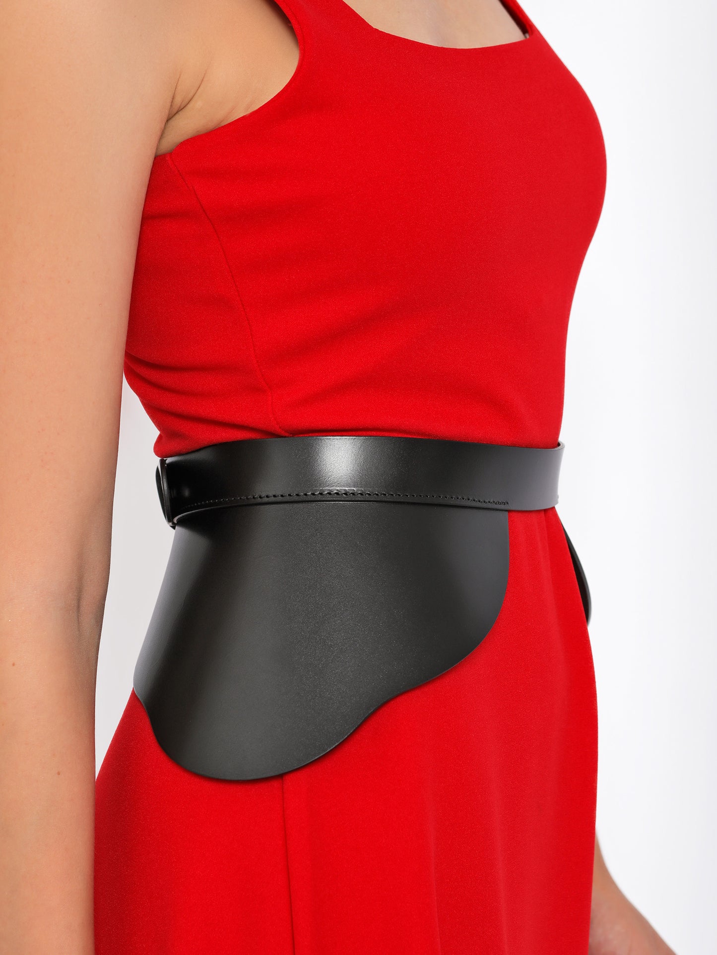 Side view of black leather high waist belt being worn over red dress.