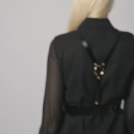 Video of black leather harness worn by model over black shirt.