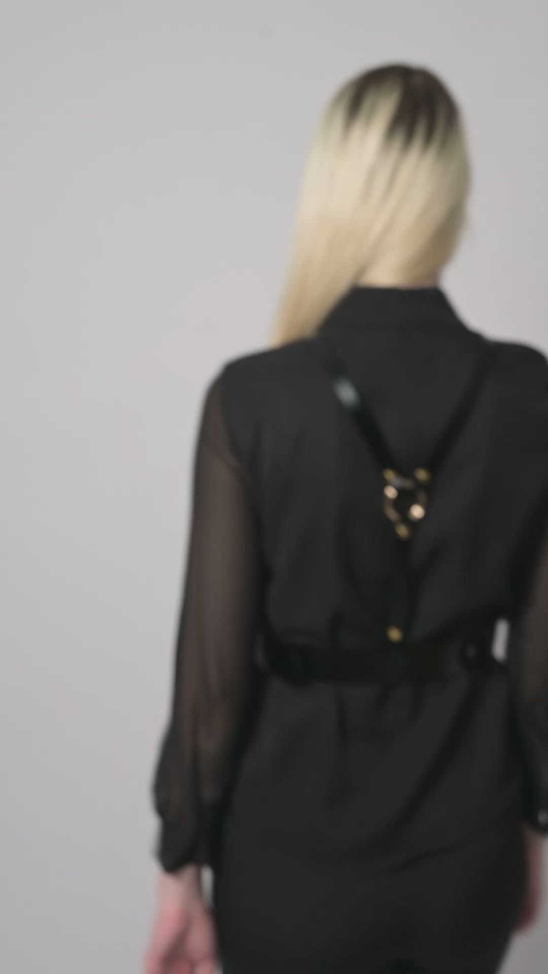 Video of black leather harness worn by model over black shirt.