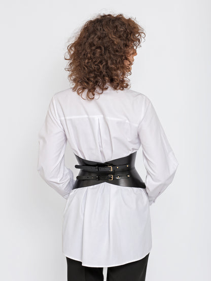 Back view of black leather corset belt worn over white shirt by model.