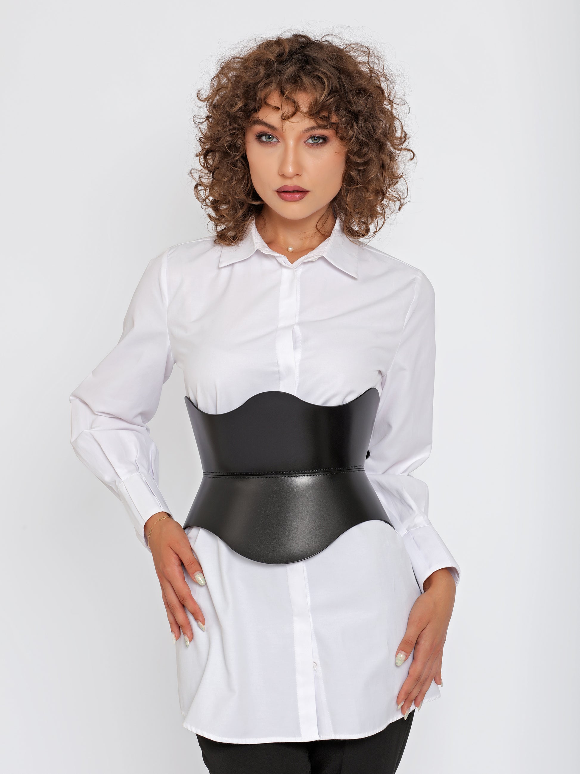Front view of black leather corset belt worn over white shirt by model.