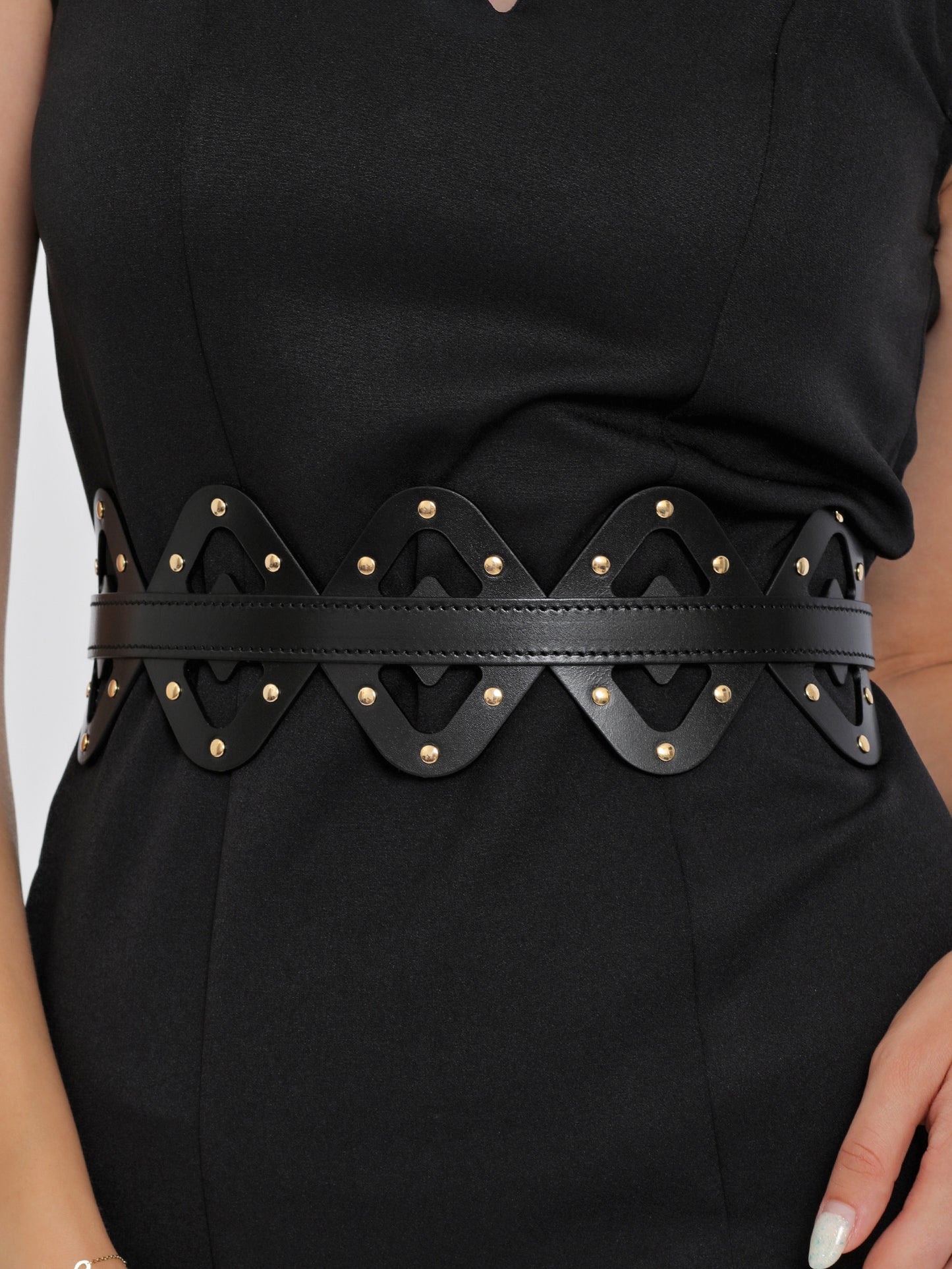 Close view of high waist leather belt being worn over black dress.